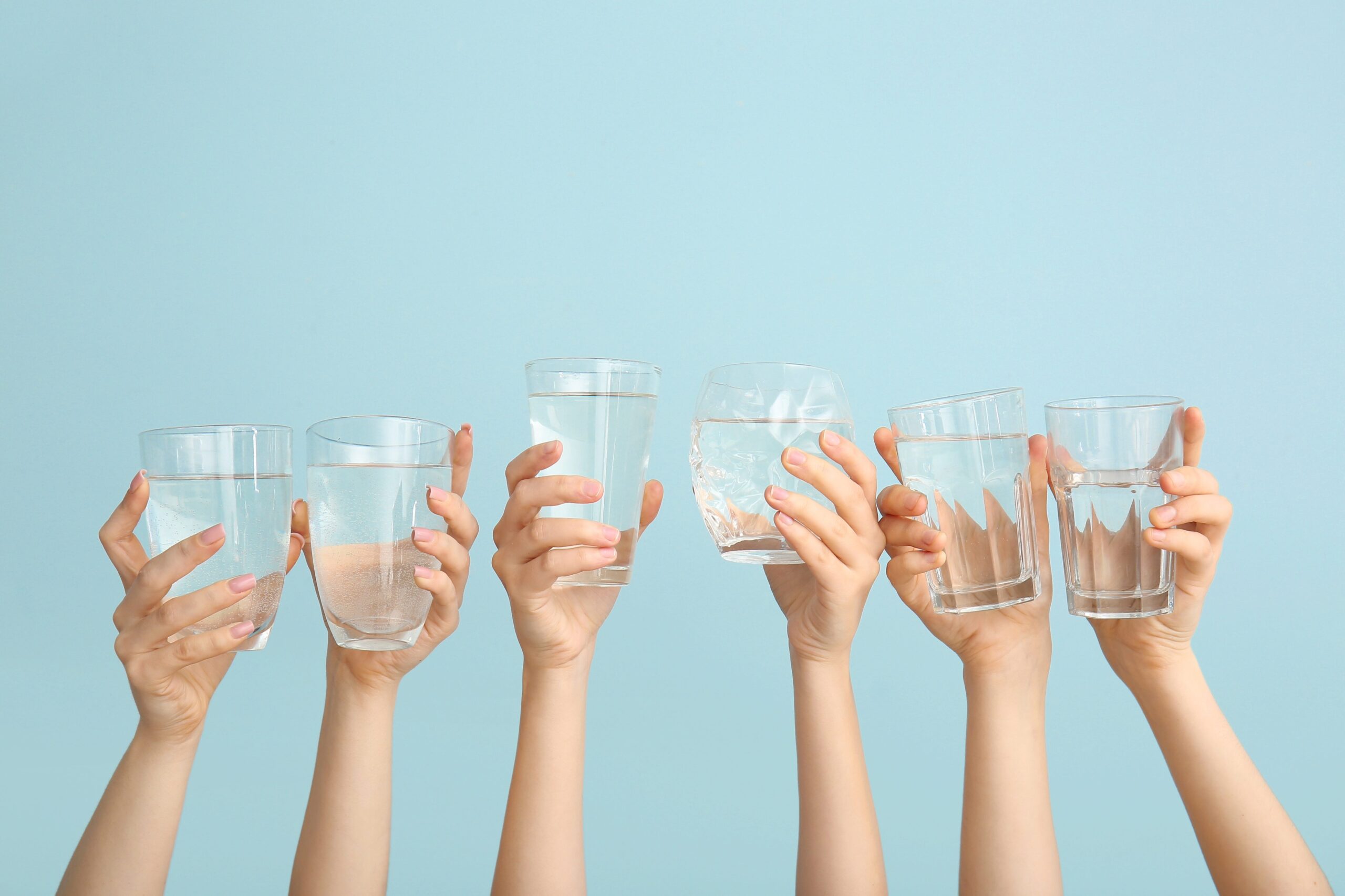 hands holding water glasses. hydration is important for gut function