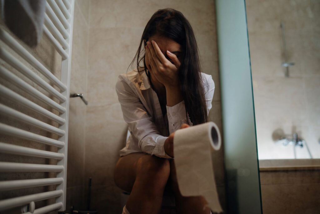 Woman sitting on the toilet, sad, embarrassed